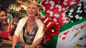 Joyful Women Gambling With Friends, Casino Table with Poker Chips, Dice, and Poker Cards