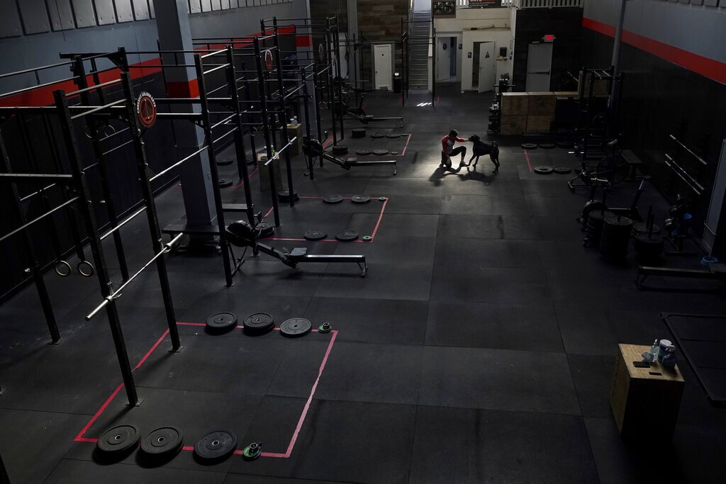 CrossFit Golden Gate owner Danielle Rabkin plays with her dog Bruno while interviewed at her gym in San Francisco, Thursday, Nov. 12, 2020. State and local health officials are blaming private gatherings for a surge in California coronavirus cases to levels unseen in months. That has business owners and some health experts scratching their heads over why the state's response has instead been to impose more restrictions on businesses like restaurants and gymnasiums in areas that have been backsliding. (AP Photo/Jeff Chiu)