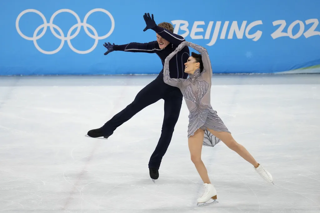 A pair of figure skaters perform a synchronized pose on the ice at the Beijing Winter Olympics
