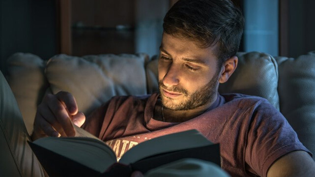 Guy Reading Book On Couch
